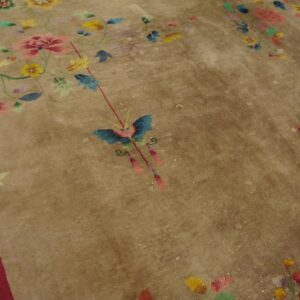 Low pile tan rug featuring multi-color floral designs, a central butterfly, and a red border section.