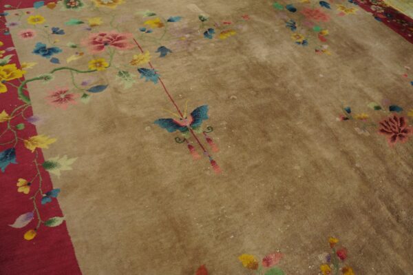 Low pile tan rug featuring multi-color floral designs, a central butterfly, and a red border section.