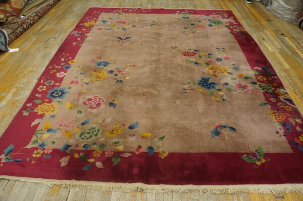 Large taupe rug with a red border and scattered multicolor floral and butterfly patterns on wood floor.