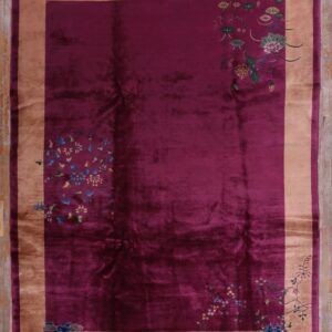 Velvety magenta rug with a golden-tan border and colorful floral details, laid on rustic wood planks.