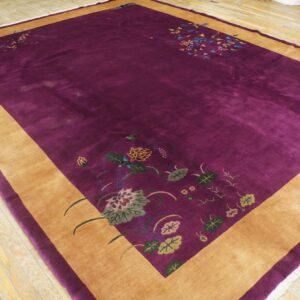 Deep purple high-pile rug featuring a wide tan border and colorful stylized floral corner designs on hardwood.