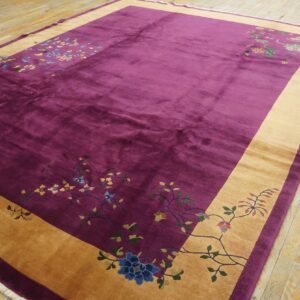 Velvety magenta rug with a gold border and floral patterns rests on distressed wooden floorboards.