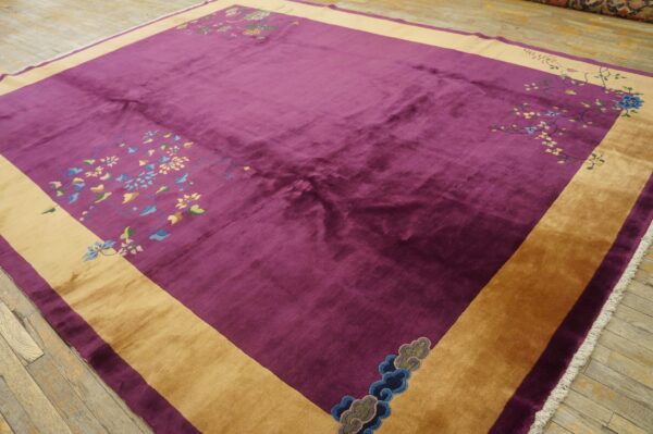 Plush, deep purple rug with a wide gold border and intricate floral corner designs on wood floor.