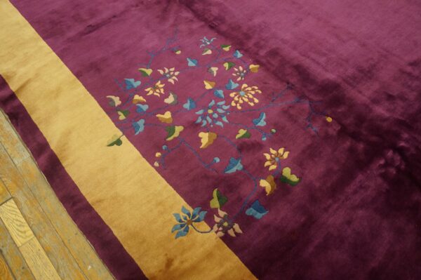 Deep magenta rug with a gold diagonal stripe and multicolored floral details on wood flooring.