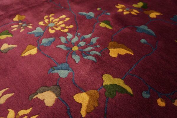 Deep magenta rug with a dense pile and stylized floral patterns in gold, blue, and various greens.