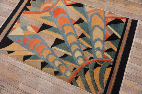 Geometric art deco rug featuring orange, teal, gold, and black patterns rests on rustic wooden floor planks.
