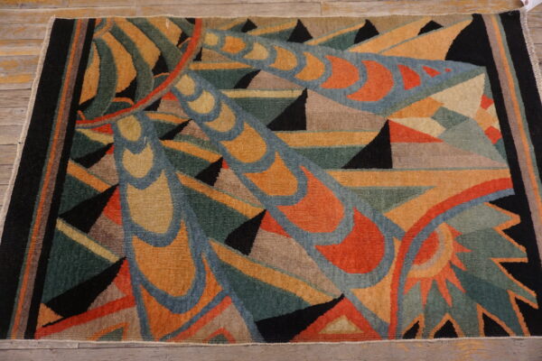 Teal, orange, black, and blue geometric rug with stylized curvilinear design on wood planks.