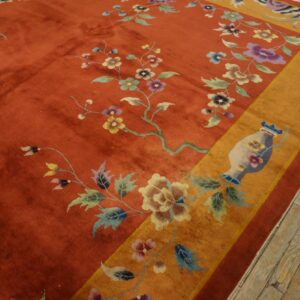 Orange high-pile rug with a detailed floral pattern, wide gold border, visible on weathered wooden floors.