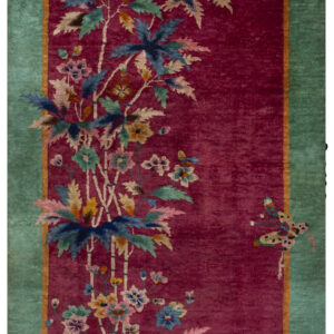 Crimson rug with a teal border and multi-colored botanical motifs, including a vase and butterfly.