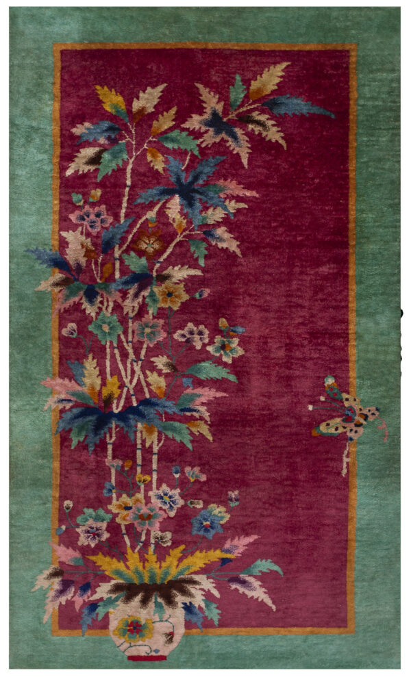 Crimson rug with a teal border and multi-colored botanical motifs, including a vase and butterfly.