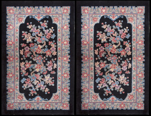 Matching pair of black rugs featuring a large, ornate floral design in dusty rose, blue, and lavender with thick borders.