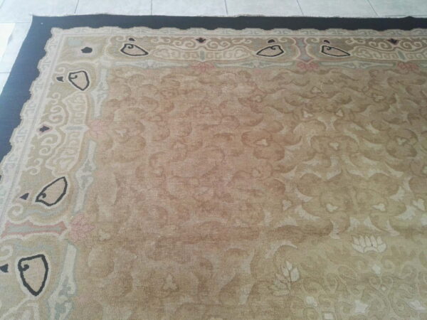 Faded beige low-pile rug with stylized cream, black, and pink borders rests on light tiled flooring.