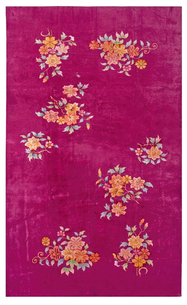 High-pile magenta rug with scattered clusters of multi-colored floral designs and a subtle carved background pattern.
