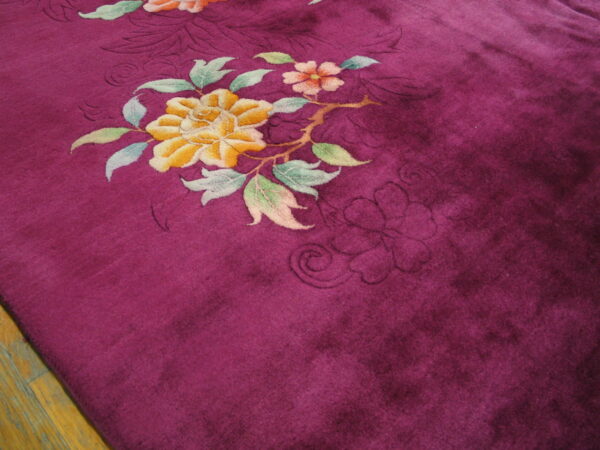 Plush deep purple rug featuring carved yellow and pink floral designs over wooden floorboards.