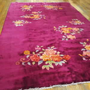 Plush magenta rug featuring scattered orange, yellow, and pink floral motifs on a wood plank floor.