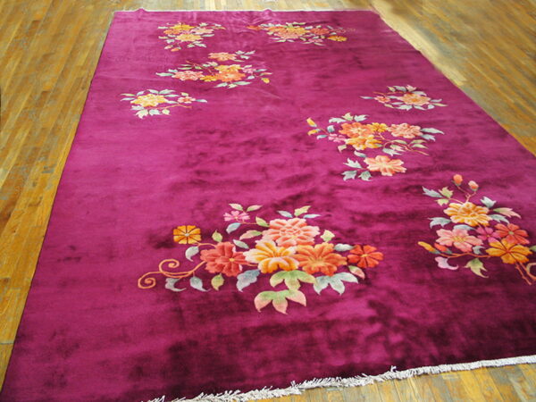 Plush magenta rug featuring scattered orange, yellow, and pink floral motifs on a wood plank floor.