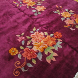 Soft purple rug with high pile showing carved floral clusters in orange, pink, and muted green.