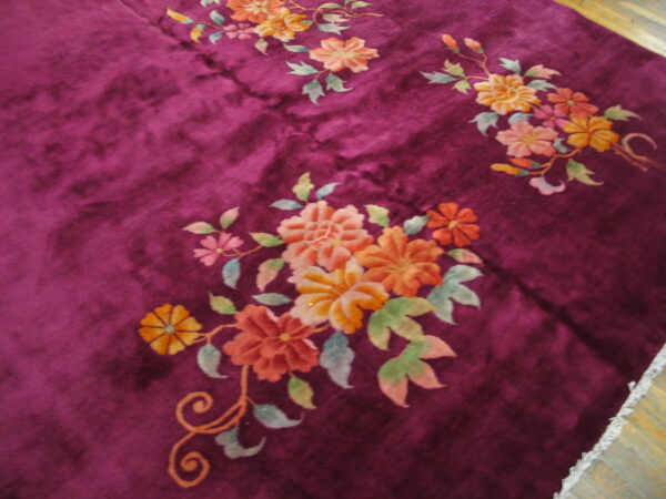 Soft purple rug with high pile showing carved floral clusters in orange, pink, and muted green.