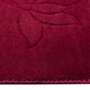 Deep burgundy rug detail highlighting plush texture and a faint tone-on-tone floral design.
