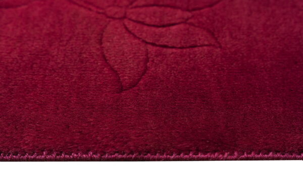 Deep burgundy rug detail highlighting plush texture and a faint tone-on-tone floral design.
