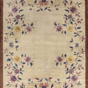 Beige rug with a brown border and an open vine pattern featuring purple, blue, and yellow stylized flowers.