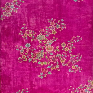 Vibrant pink rug with a soft sheen features scattered multicolored floral and vine motifs.