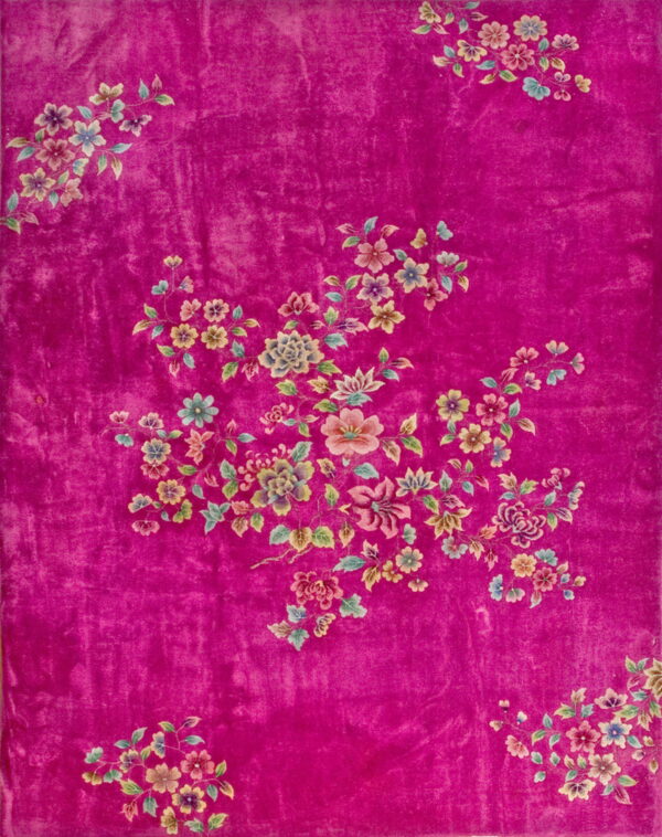 Vibrant pink rug with a soft sheen features scattered multicolored floral and vine motifs.