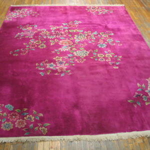 Magenta rug featuring scattered pastel floral sprays rests on rustic hardwood planks.