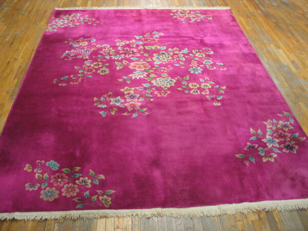 Magenta rug featuring scattered pastel floral sprays rests on rustic hardwood planks.