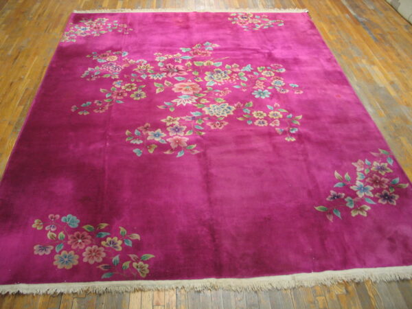 Vibrant magenta rug featuring scattered pink and blue floral patterns on a warm hardwood floor.