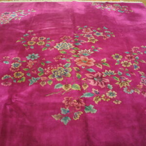 Magenta rug with visible sheen and scattered pastel floral branches lying on a wood floor.