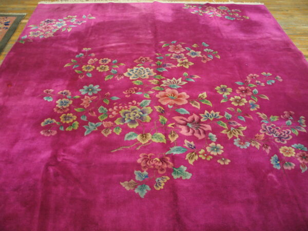 Magenta rug with visible sheen and scattered pastel floral branches lying on a wood floor.