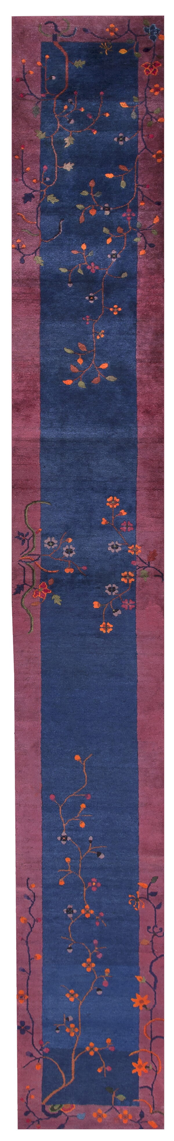 Plush runner rug with a deep blue center framed by mauve stripes and colorful blooming vines.