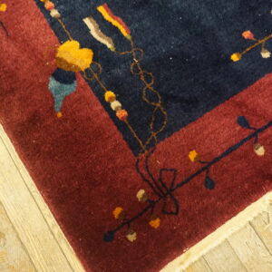 Dark blue and maroon high-pile rug detail showing colorful floral and vine motifs on wood flooring.