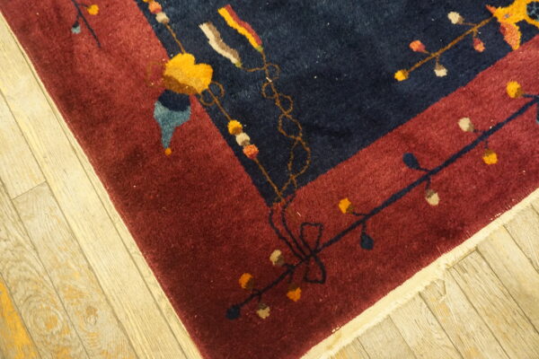 Dark blue and maroon high-pile rug detail showing colorful floral and vine motifs on wood flooring.