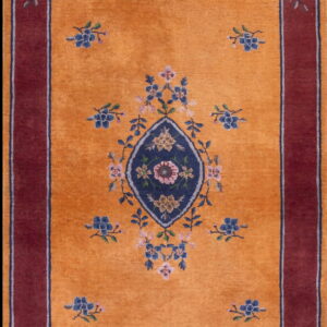 Orange runner rug with a central blue floral medallion, scattered blue motifs, and a wide maroon border.