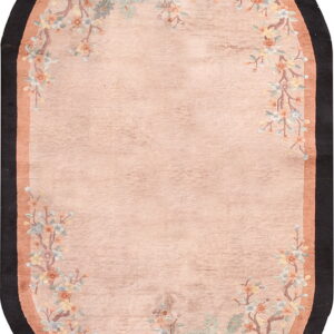 Oval pink rug featuring a floral and bird pattern border with terracotta and black edges.