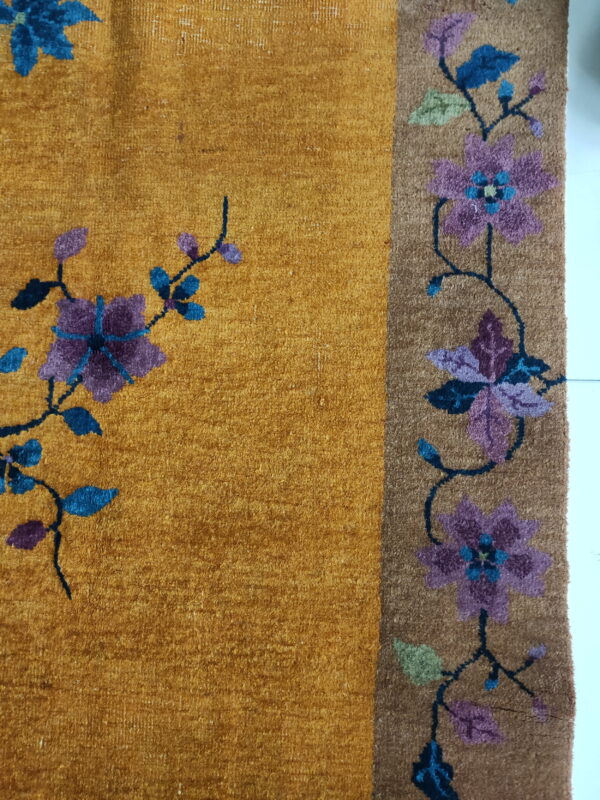 Golden yellow high-pile rug with stylized purple and blue flowers and a contrasting brown floral border.