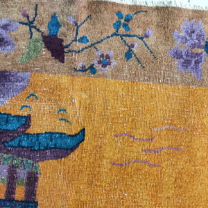 Textured gold rug featuring floral motifs and a purple and teal architectural or boat design.