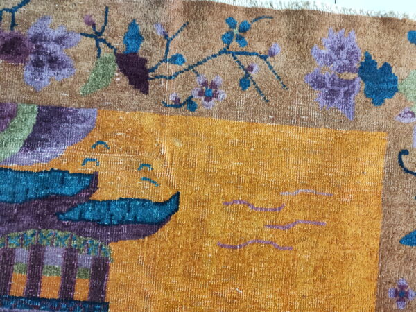 Textured gold rug featuring floral motifs and a purple and teal architectural or boat design.