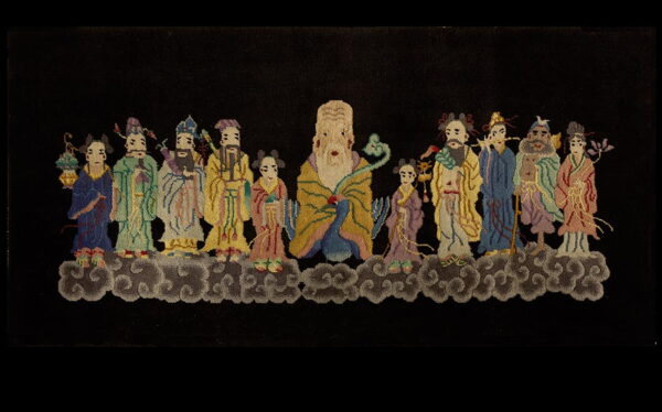 Black pile rug featuring a detailed, colorful tableau of stylized figures above swirling gray clouds.