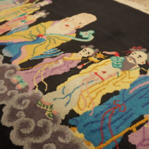 A dark-piled rug featuring a multicolor pattern of stylized human figures floating on carved gray clouds.