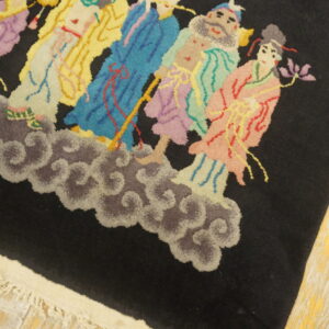 A high-pile black rug features a brightly colored pattern of figures on clouds over worn wood floors.