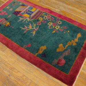 Teal low-pile rug with a multicolored architectural and floral pattern and a bright magenta border sits on wood planks.