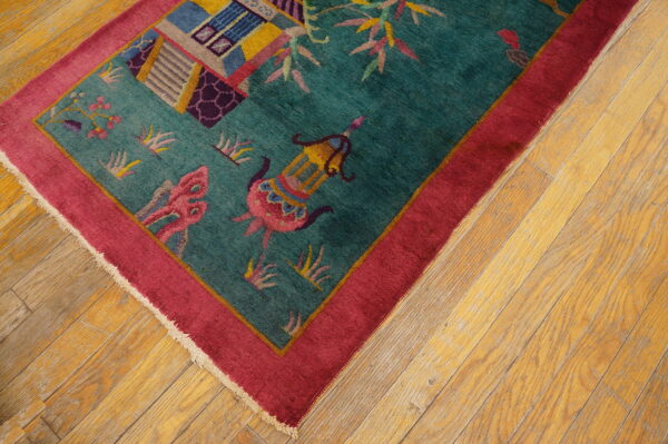 Teal rug featuring pink and yellow figural patterns, a wide magenta border, set on light wood flooring.