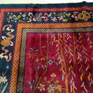 Plush rug with a crimson field and navy border, detailed with multicolored geometric and floral patterns.