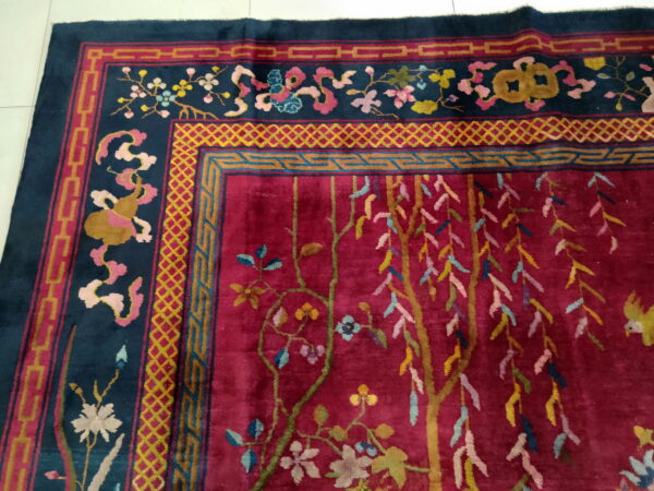 Plush rug with a crimson field and navy border, detailed with multicolored geometric and floral patterns.