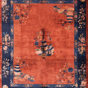 Rust-colored rug with a central pagoda scene bordered by detailed navy blue floral and architectural motifs.