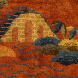 Rustic orange rug close-up with a stylized pattern of mountains and waves in blue, gold, and brown.
