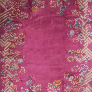 Fuchsia pink rug with colorful floral motifs trailing over a light geometric basketweave border.